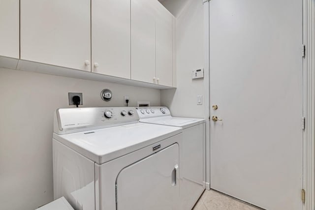 laundry area featuring cabinets, light tile patterned floors, and washer and clothes dryer