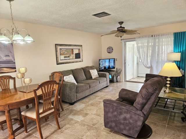 living room with ceiling fan with notable chandelier and a textured ceiling