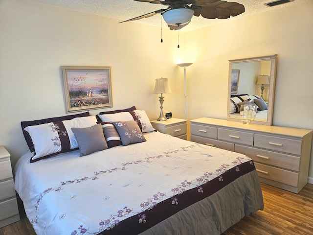 bedroom featuring a textured ceiling, ceiling fan, and dark hardwood / wood-style floors