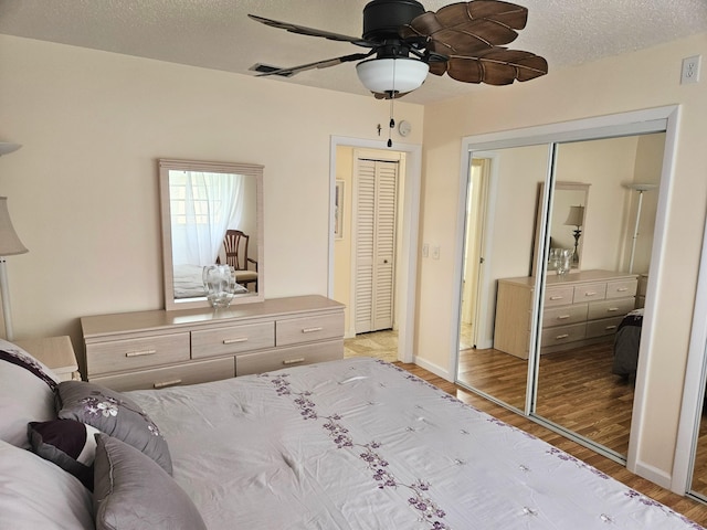 unfurnished bedroom with two closets, ceiling fan, light hardwood / wood-style floors, and a textured ceiling