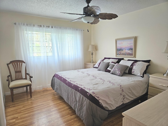 bedroom featuring ceiling fan, light wood-type flooring, and a textured ceiling