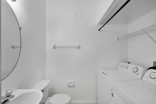 bathroom with toilet, sink, and washing machine and clothes dryer