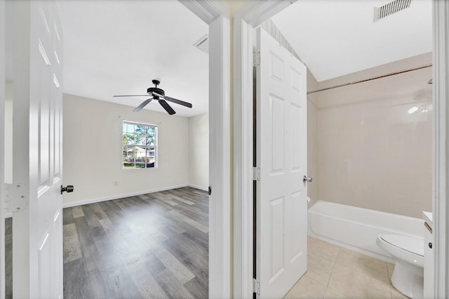 full bathroom with shower / bathtub combination, vanity, ceiling fan, hardwood / wood-style flooring, and toilet