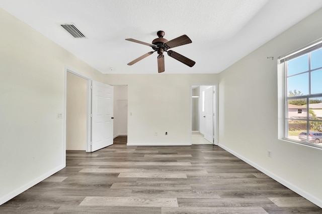 spare room with a textured ceiling, light wood-type flooring, and ceiling fan