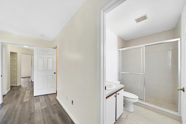 bathroom with wood-type flooring, vanity, toilet, and walk in shower