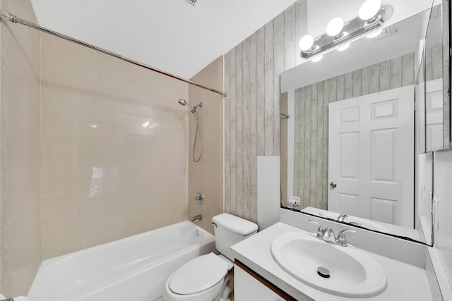 full bathroom with wood walls, vanity, tiled shower / bath combo, and toilet