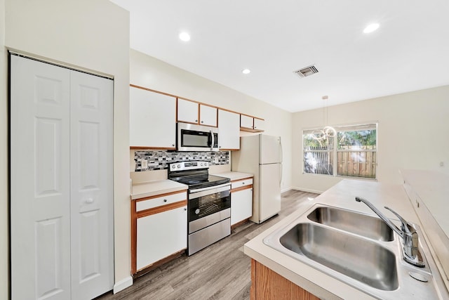 kitchen with stainless steel appliances, sink, decorative light fixtures, light hardwood / wood-style flooring, and white cabinetry