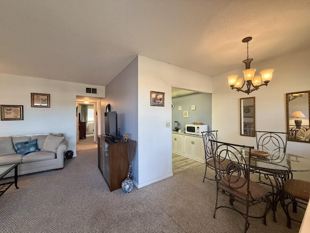 carpeted dining room featuring a textured ceiling and a notable chandelier