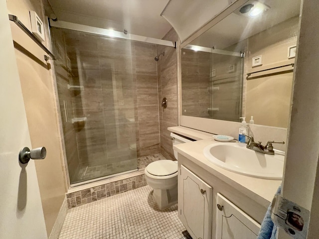 bathroom featuring tile patterned flooring, vanity, toilet, and a shower with door