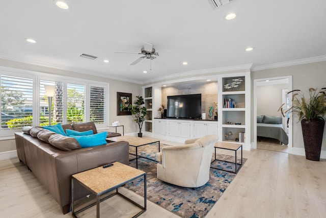 living room with built in shelves, light wood-type flooring, ceiling fan, and crown molding