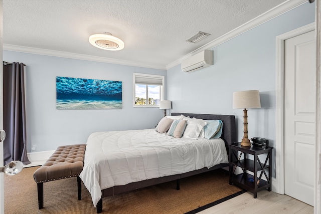 bedroom featuring a textured ceiling, light wood-type flooring, a wall unit AC, and ornamental molding