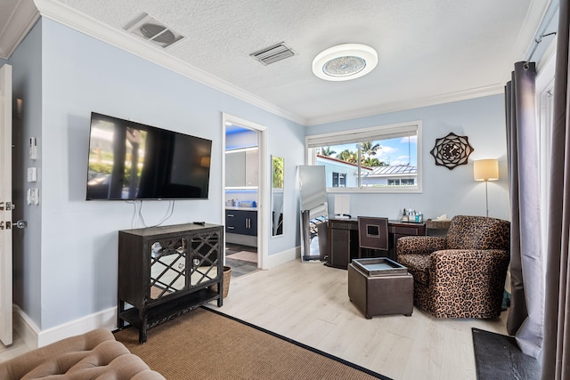 living room featuring a textured ceiling, light wood-type flooring, and crown molding