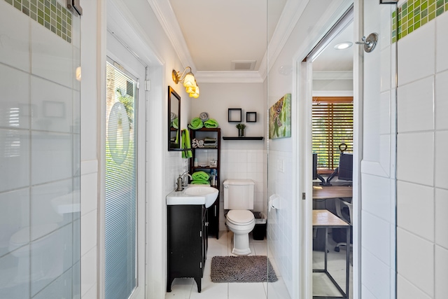 bathroom with tile patterned floors, toilet, vanity, tile walls, and ornamental molding