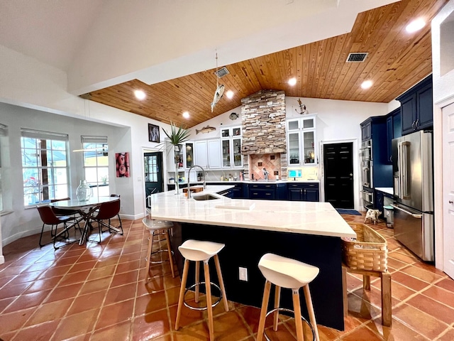 kitchen with wooden ceiling, a breakfast bar area, high end refrigerator, sink, and blue cabinets