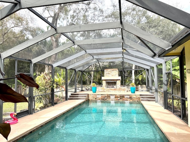 view of swimming pool with pool water feature, a patio area, an outdoor stone fireplace, and glass enclosure