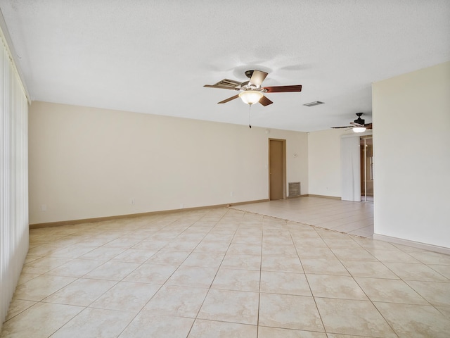 unfurnished room with ceiling fan, light tile patterned flooring, and a textured ceiling