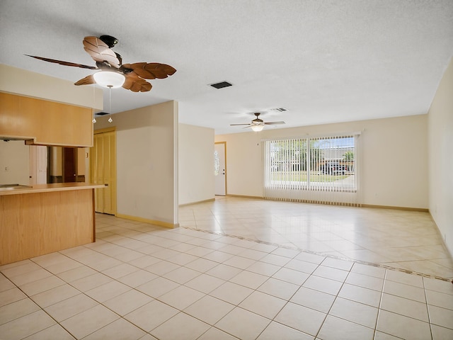 unfurnished living room with ceiling fan, light tile patterned floors, and a textured ceiling