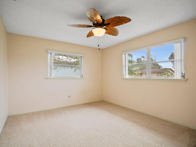 spare room featuring a wealth of natural light, carpet, a textured ceiling, and ceiling fan