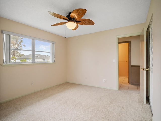 carpeted empty room with ceiling fan and a textured ceiling