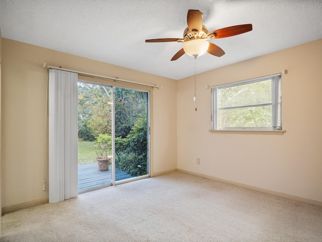 spare room featuring ceiling fan, a textured ceiling, a wealth of natural light, and light carpet