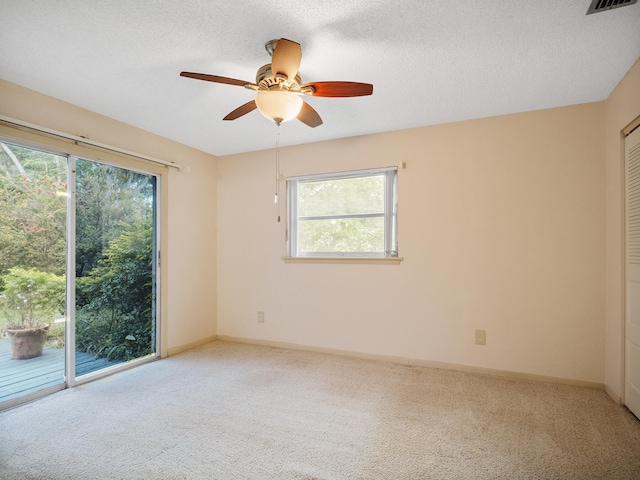 carpeted empty room featuring ceiling fan, a textured ceiling, and a wealth of natural light