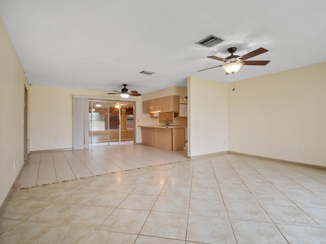 unfurnished room featuring ceiling fan, light tile patterned floors, and a textured ceiling