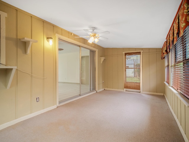 unfurnished room featuring ceiling fan, carpet floors, wooden walls, and lofted ceiling