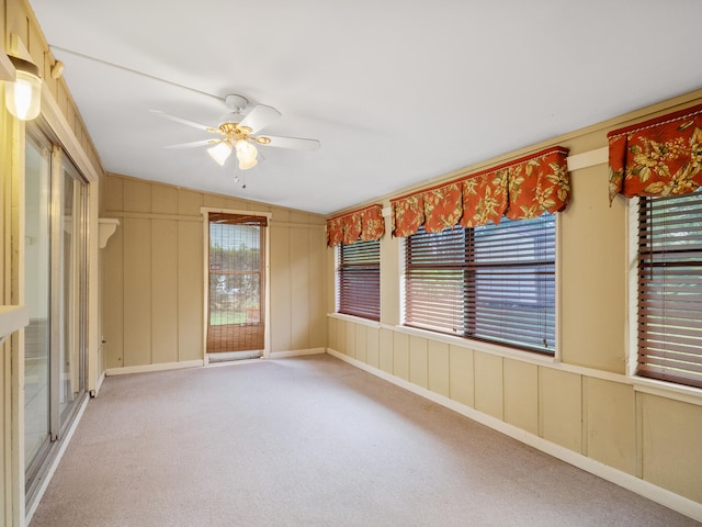 carpeted spare room featuring ceiling fan, lofted ceiling, and a wealth of natural light