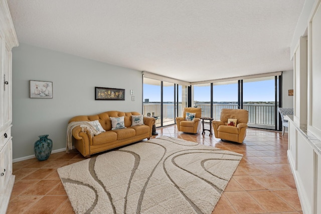 tiled living room with expansive windows, a water view, a wealth of natural light, and a textured ceiling