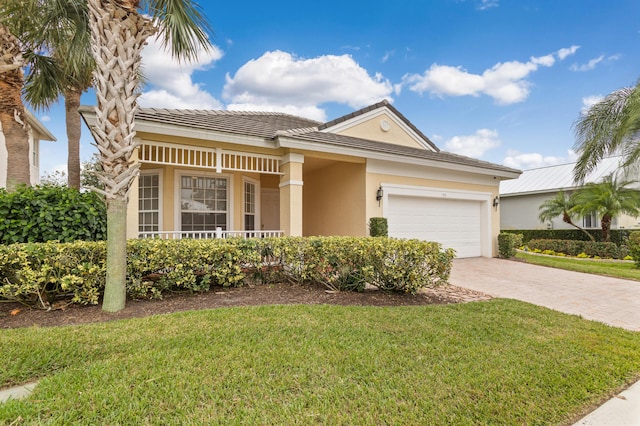 ranch-style home with stucco siding, a tile roof, an attached garage, decorative driveway, and a front yard