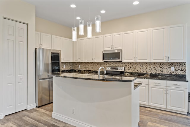 kitchen with white cabinets, light wood-type flooring, stainless steel appliances, and a kitchen island with sink