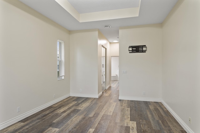 unfurnished room with a tray ceiling and dark hardwood / wood-style floors