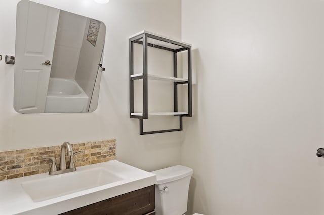 bathroom with vanity, toilet, a tub to relax in, and tasteful backsplash