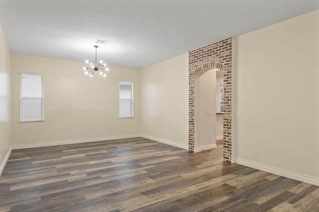 empty room featuring a notable chandelier and dark hardwood / wood-style floors