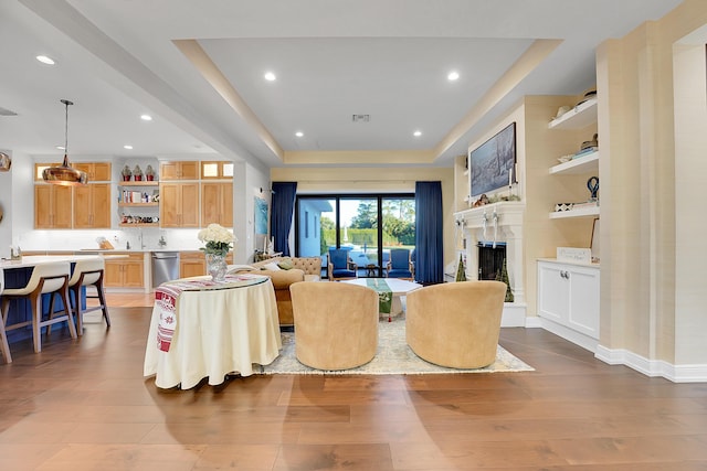 living room with a raised ceiling and wood-type flooring