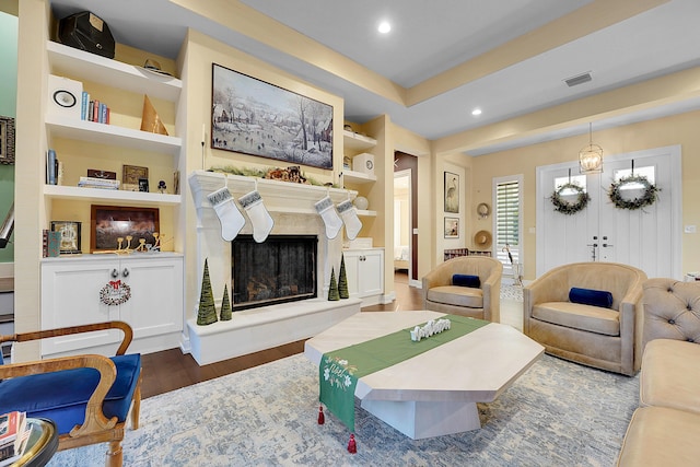 living room featuring dark hardwood / wood-style floors, built in shelves, and an inviting chandelier