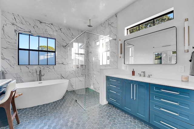 bathroom featuring plus walk in shower, vanity, tile walls, and tile patterned flooring