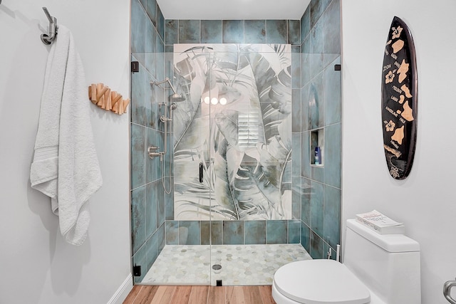 bathroom featuring hardwood / wood-style flooring, toilet, and a shower with door