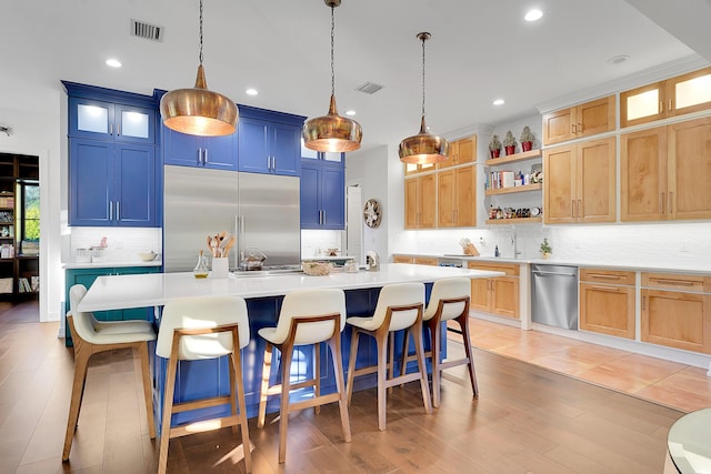 kitchen with hardwood / wood-style floors, an island with sink, and appliances with stainless steel finishes