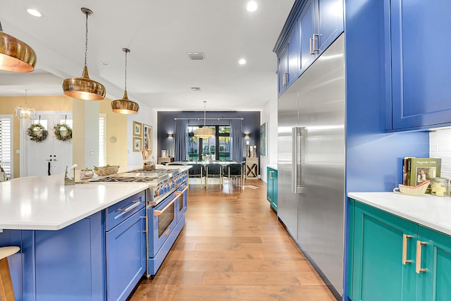 kitchen featuring pendant lighting, light wood-type flooring, blue cabinets, and high quality appliances