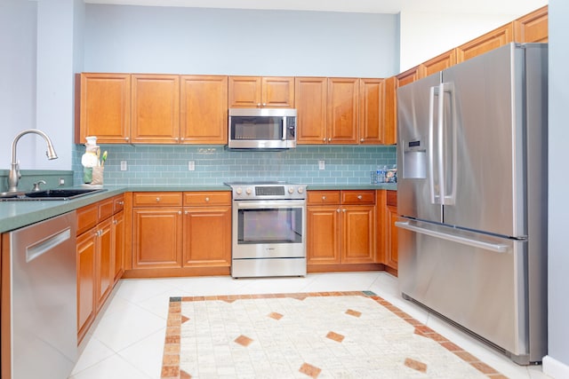 kitchen featuring appliances with stainless steel finishes, backsplash, light tile patterned floors, and sink