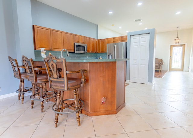 kitchen with pendant lighting, a breakfast bar area, light tile patterned floors, kitchen peninsula, and stainless steel appliances