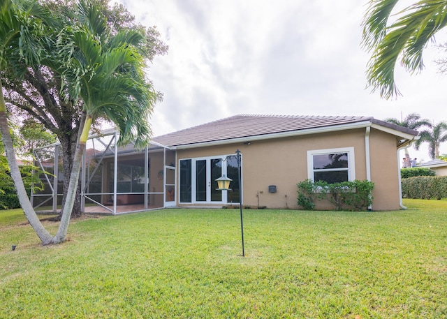 back of property with a lawn and glass enclosure