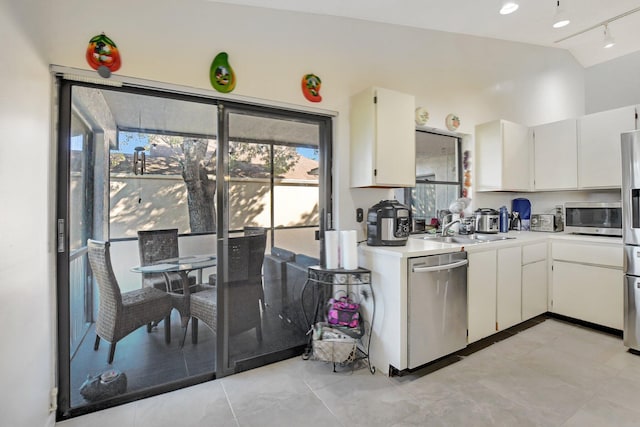 kitchen with white cabinets, rail lighting, sink, vaulted ceiling, and appliances with stainless steel finishes