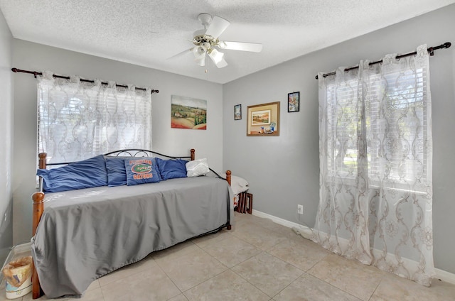 tiled bedroom with ceiling fan and a textured ceiling