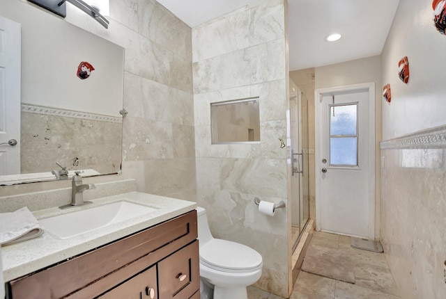 bathroom with vanity, toilet, tile walls, and walk in shower