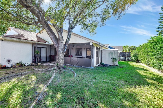 back of property with a lawn, a sunroom, and ceiling fan