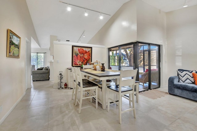 dining room with plenty of natural light, high vaulted ceiling, track lighting, and light tile patterned floors