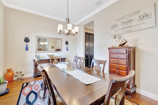 dining room with light hardwood / wood-style floors, crown molding, and a chandelier