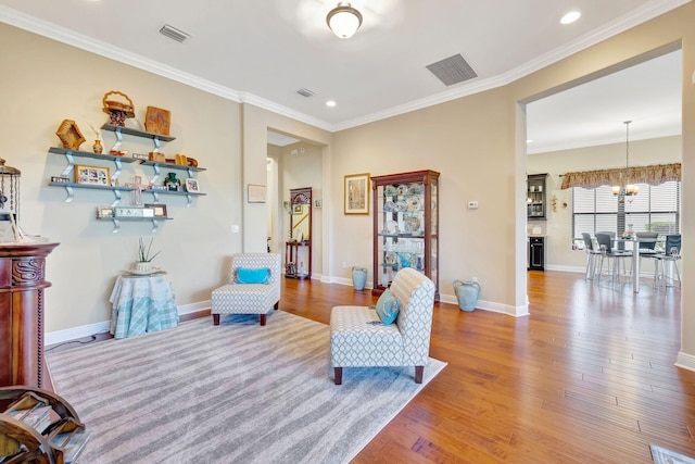 sitting room featuring a chandelier, light hardwood / wood-style flooring, and crown molding